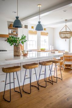 a kitchen island with four stools next to it and a potted plant on the counter