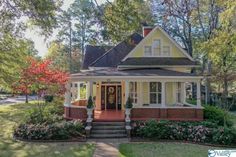 a yellow house with white trim on the front porch and steps leading up to it