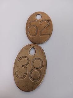 two metal tags with numbers on them sitting next to each other