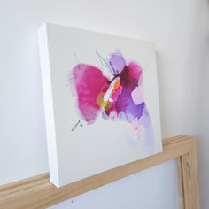 a painting is hanging on the wall next to a wooden framed object with a butterfly painted on it