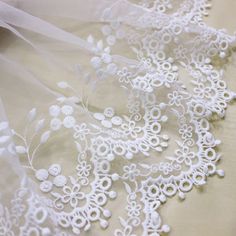 white lace with flowers and leaves is on the fabric, it looks like something out of an antique book