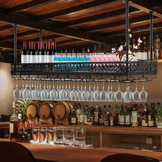 a bar with lots of wine glasses hanging from the ceiling and bottles on the shelves