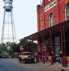 an old car is parked in front of a building with a water tower on top