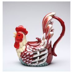 a red and white rooster figurine sitting on top of a table next to a gray background