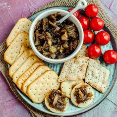 a plate with crackers, tomatoes and mushrooms on it