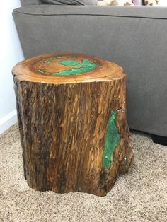 a dog laying on the floor next to a tree stump with a green paint job