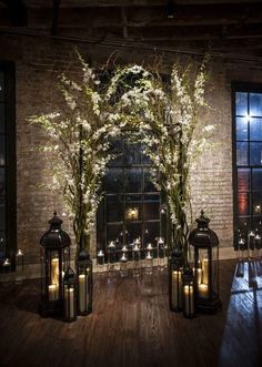 an indoor area with candles and flowers in vases on the floor next to windows