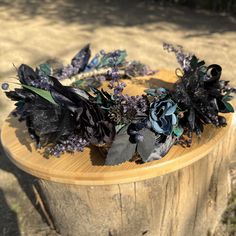 a wreath made out of flowers and leaves sitting on top of a wooden stump in the grass