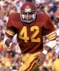 a football player running with the ball in his hand and people watching from the stands