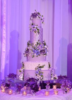 a wedding cake with purple flowers and candles