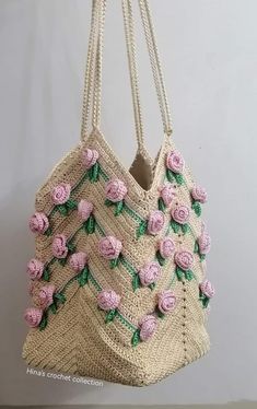 a handbag with pink roses on it hanging from a hook in front of a white wall