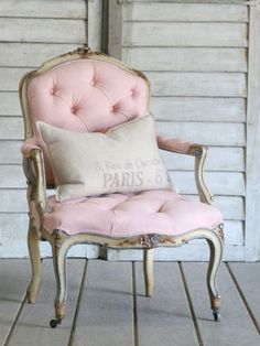 a pink chair sitting on top of a wooden floor next to a white wall and door