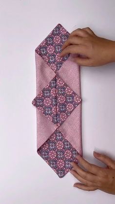 a person is holding a pink tie on a white surface with one hand and the other