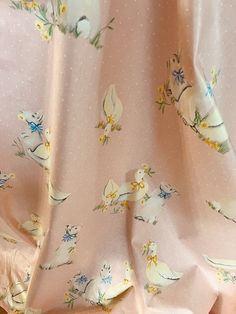 the fabric is pink with yellow flowers and birds on it, as well as polka dots