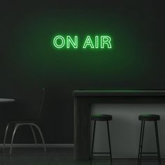 a neon sign that reads on air above two stools