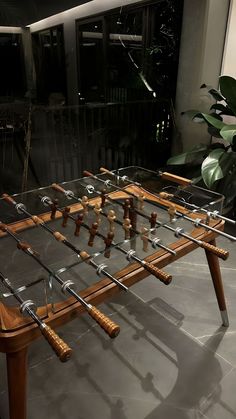 a foosball table with wooden handles and glass top sitting in front of a plant