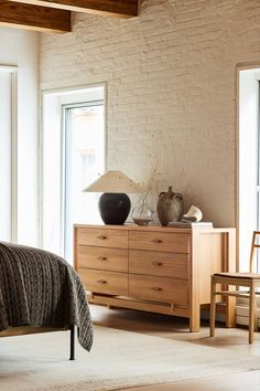 a bedroom scene with focus on the dresser and bed side table in the foreground