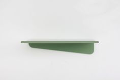 a green shelf sitting on top of a white wall