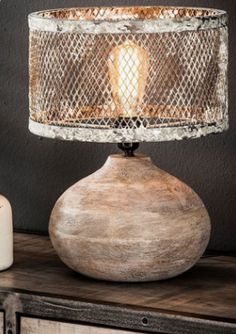 a wooden table with a lamp on top of it next to a bottle and candle