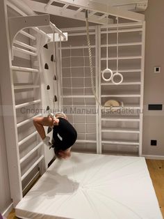 a woman standing on top of a white mat in front of a wall with shelves