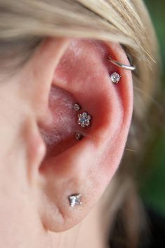 a close up of a person's ear with three small piercings on it