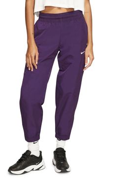 Nike NRG Women's Cropper Track Pants Style#: CQ4003-525 Purple Size: Medium (XS=0-2, S=4-6, M=8-10, L=12-14). These vintage-style track pants in smooth, swishy woven nylon are a throwback classic that feels fresh for today. High rise 26 1/2" inseam; 10" leg opening; 10 1/2" front rise; 15 1/2" back rise (size Medium) Elastic/drawcord waist Side zip pockets Side-zip elastic hems Mesh lining 100% nylon Machine wash, line dry Imported