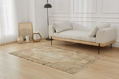 a white couch sitting on top of a hard wood floor next to a lamp and window