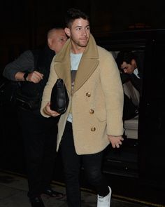 a man in a tan coat and white sneakers