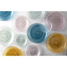 several different colored glass plates sitting on top of a table next to eachother