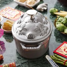 a silver pot sitting on top of a table next to other dishes and utensils