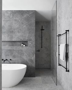 a white bath tub sitting in a bathroom next to a wall mounted shower faucet