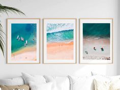 three framed pictures hang on the wall above a couch in a living room with white furniture