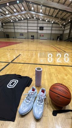 shoes, t - shirt and basketball are on the floor in an indoor gym area