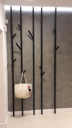 a white bag hanging on the wall next to some black metal poles and a coat rack