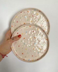 two plates with confetti designs on them are being held by a woman's hand