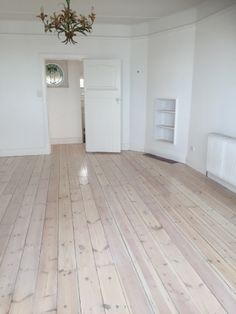 an empty room with hard wood floors and white walls