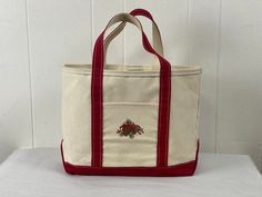 "Vintage 1990s canvas bag, tote, duffle. Color is white with deep red trim. Made by  L.L. Bean Boat and Tote. Has two handles and one main compartment with a small side pocket embroidered with acorns and a red ribbon. Sort of a Christmas theme.  Bag measures 17\" wide, 12\" tall and 5\" thick. Handles hang down 7\". In very good condition with some minor dirt spots, see picture." Boat And Tote Ll Bean, Ll Bean Bag, Ll Bean Tote, Boat And Tote, Boat Tote, Canvas Duffle Bag, Hanging Toiletry Bag, Mini Crossbody Purse, Ll Bean Women