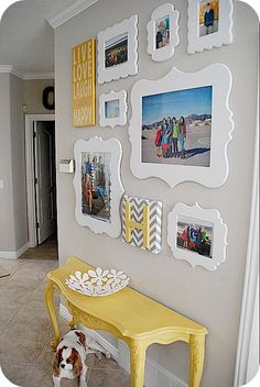 a yellow table with pictures on it and a dog standing in front of the wall