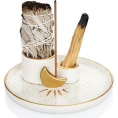 two sticks sticking out of a cup on top of a white plate with gold trim