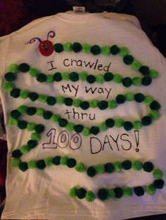 a white t - shirt with green beads on it that says i crawled my way thru 100 days