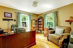 a living room filled with furniture and a book shelf next to a wooden desk in front of a window