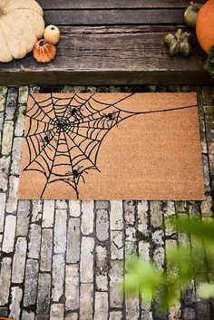 a door mat with a spiderweave on it next to pumpkins and gourds