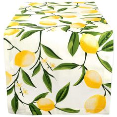 a white and yellow table cloth with lemons printed on the front, along with green leaves