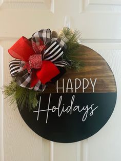 a happy holidays sign hanging on a door with red and black bows attached to it