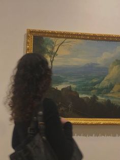 a woman is looking at a painting on the wall