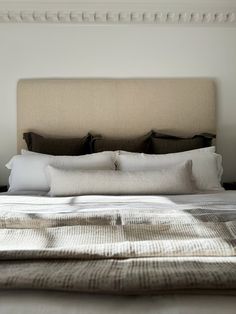 a bed with white linens and pillows on top of it's headboard