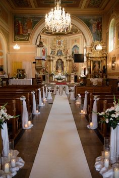 the aisle is decorated with white flowers and candles