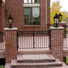 a brick house with wrought iron fence and steps leading up to the front door area