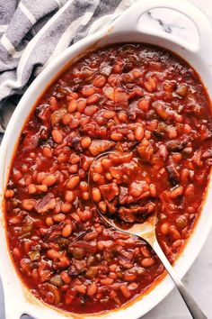 a white dish filled with baked beans on top of a table