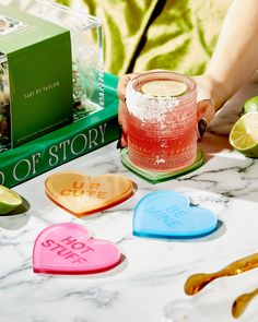 a person holding a drink in front of some books and limes on a table